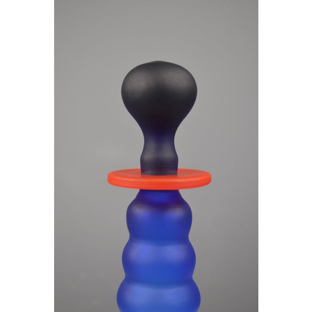 Striking blown-glass bottle with a strong Postmodern design influence. Its bold, tiered silhouette in frosted cobalt-blue...