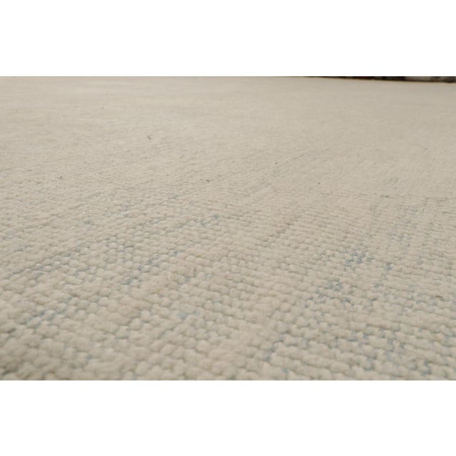Deriving a thoughtful colourplay of beige, gray and blue from our diverse yarn collection, this 13x15 rug is an artistic...
