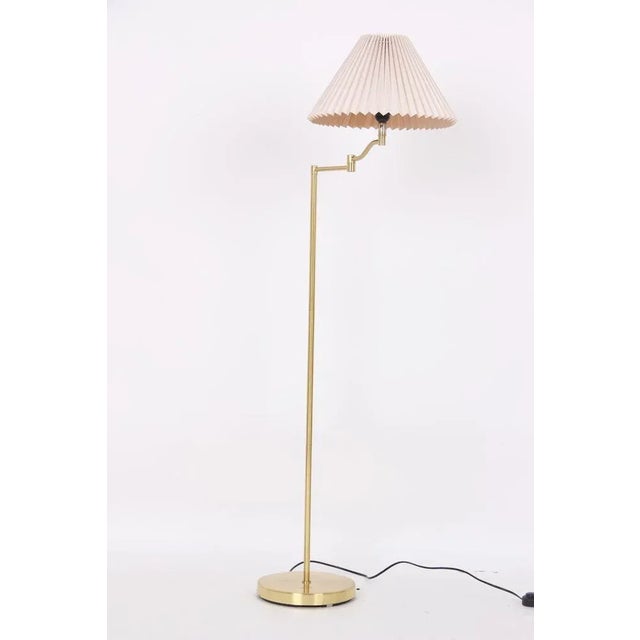 Floor lamp made of brass with swivel arm and pleated lampshade. The lamp is in a good functional state with a patina and...
