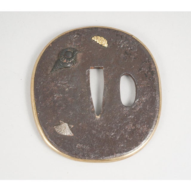 A finely crafted Japanese tsubo (handle guard) from the Edo period, made of bronze with gilded accents of gold and silver....