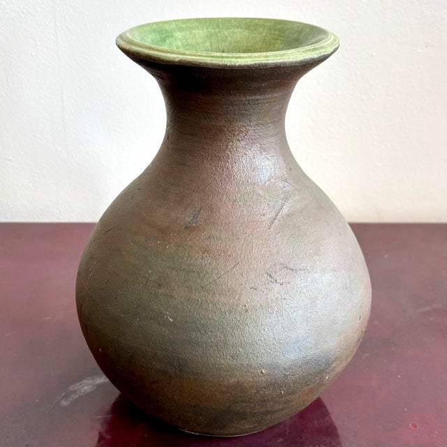 This bulbous ceramic vessel balances rustic simplicity with a subtle surprise. The unglazed exterior has a warm, earthy...