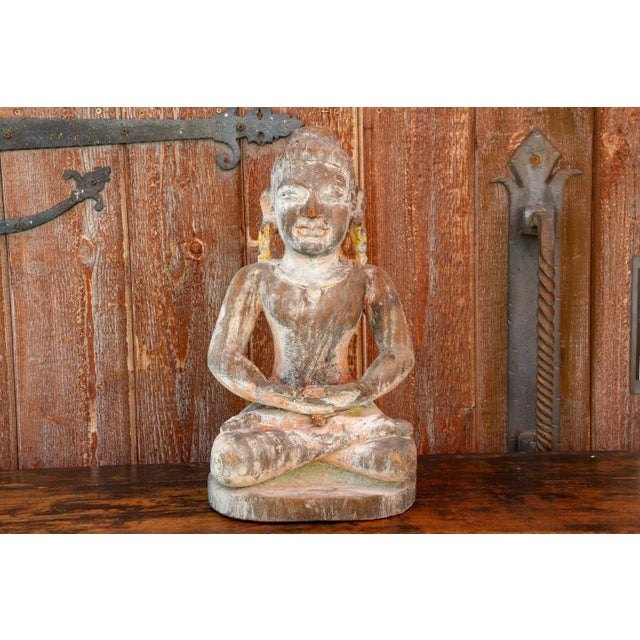 Found in Laos, its a carved wooden Buddha seated cross legged in a meditative position. This antique Buddha features a...