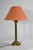 Golden bronze lamp overseen with a fabric lampshade in coral tones. The right foot is decorated with stylized leaves...