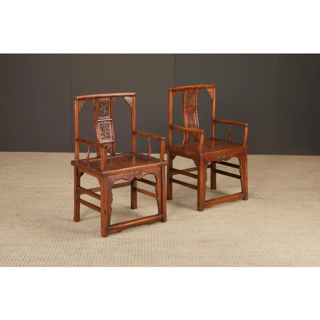 A refined pair of Chinese armchairs, crafted in solid elmwood and likely dating to the Qing Dynasty period (1644–1912),...