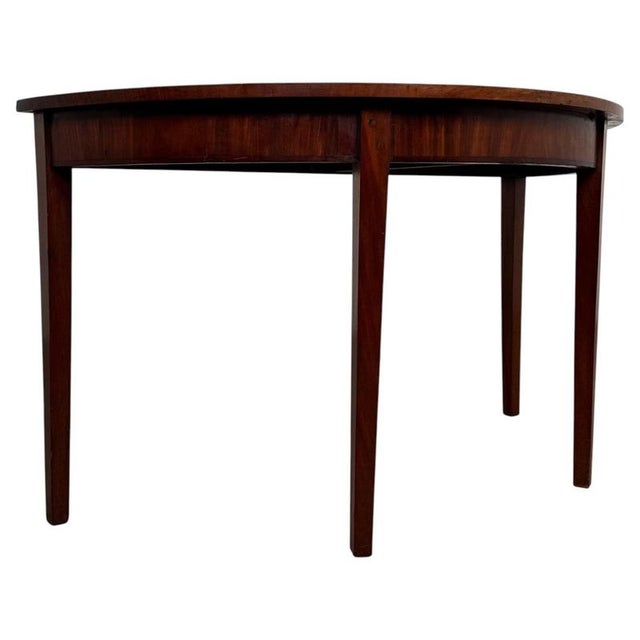 An elegant 19th-century English demi-lune table, finely crafted from mahogany and distinguished by its classical half-moon...