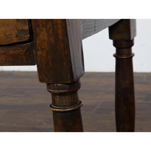 An English walnut table from the 19th century with single drawer, column-shaped legs on bun feet, plain side stretchers...