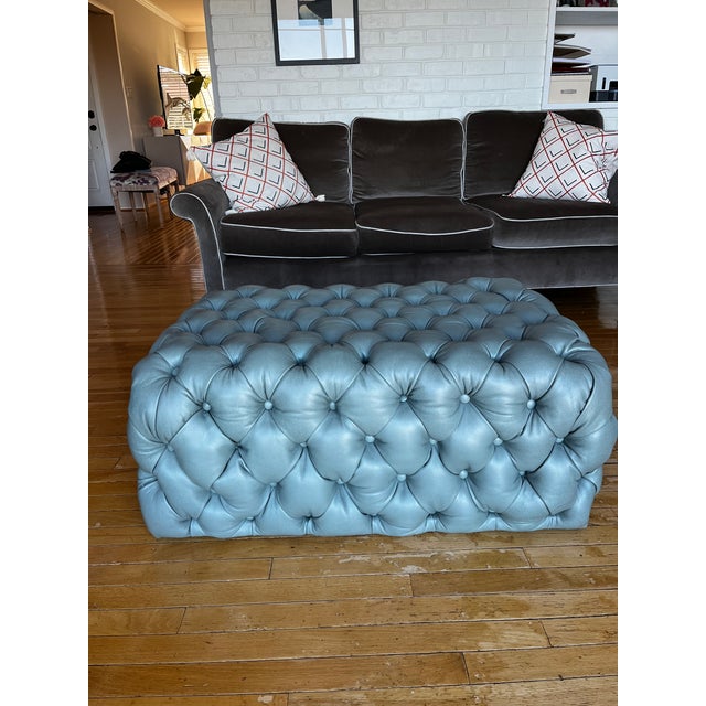 Stunning custom ottoman in tufted blue leather provides timeless sophistication to any room. Versatile piece perfect for...