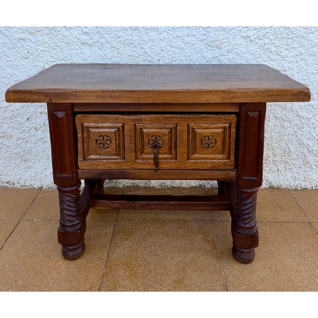 Charming Spanish side table crafted from wood, featuring a rectangular top and a beautifully carved front with geometric...