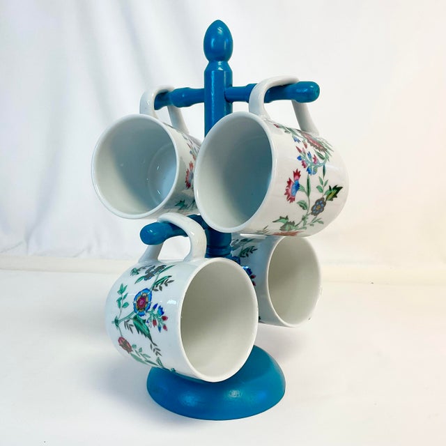 This set of 4 Coffee Mugs hand on a newly painted wood mug tree from the Mid-Century. The Mugs feature a lovely flora...