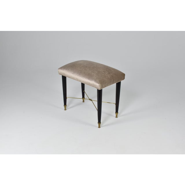 A charming Italian mid-century piano stool from the 1950s, distinguished by its sculptural wood frame and crossed brass...