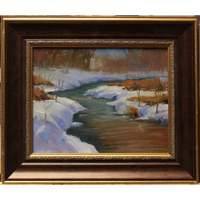 This oil on canvas depicts a serene winter landscape, where a gently flowing creek cuts through a blanket of snow. The...