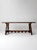 A substantial trestle table with a solid wood top and a carved base defined by shaped supports and a scalloped stretcher....