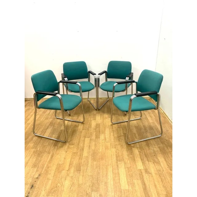 A set of four retro armchairs with armrests produced in the late 1970s and 1980s. These pieces feature a bent chrome-...