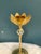 This delicate vintage brass candle holder features a tulip-style cup and a faceted glass crystal accent that adds a touch...