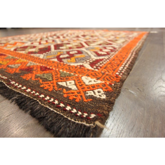 A hand-knotted Sumahk rug with a geometric pattern on a red field. Accents of orange, red and green throughout the piece....