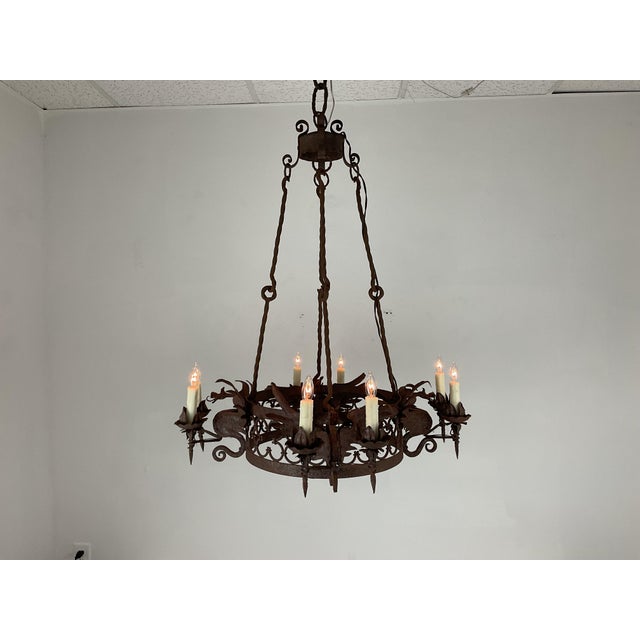An exceptional 1940s hand-forged iron chandelier featuring intricate Gothic and medieval-inspired craftsmanship. The...