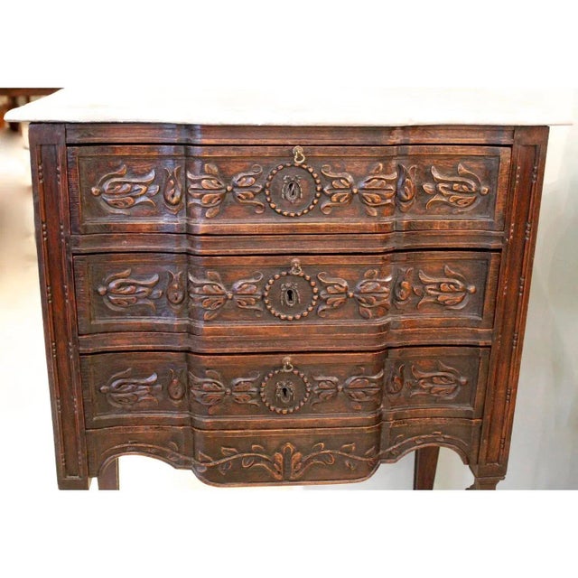 A small Italian version of a leggy carved chest of drawers, with a faux marble painted top and a charmingly carved block...