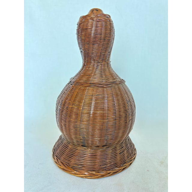 Possibly Asian or African, the wicker cover for this gourd canteen allows it to sit nicely on a flat surface for display.