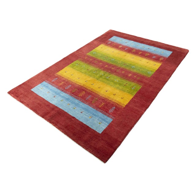 This artfully hand-knotted Gabbeh Loribaft rug impresses with bright colors and a playful striped pattern made from...