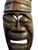 Hand-carved wooden wall mask featuring an elongated face, tiered crescent headdress, and a fierce, grimacing expression...