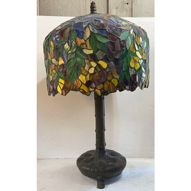 This is Tiffany style lamp has a beautiful green foliage shade with orange, red, and purple accents. With a sturdy metal...