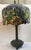 This is Tiffany style lamp has a beautiful green foliage shade with orange, red, and purple accents. With a sturdy metal...