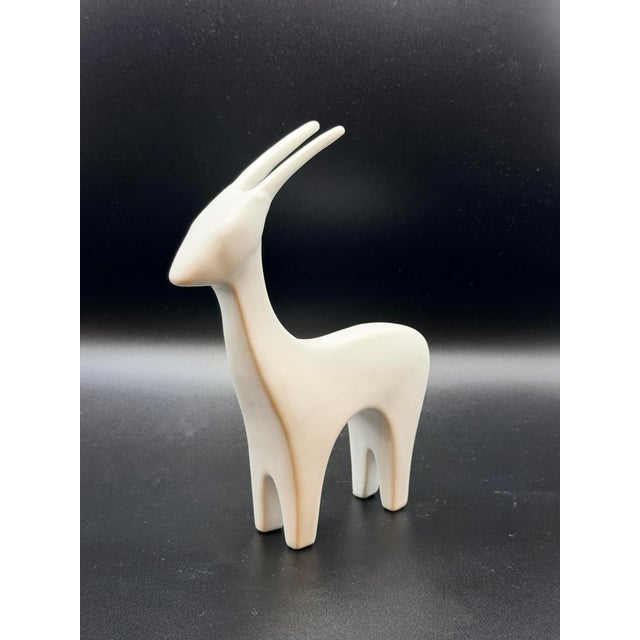 A refined minimalist antelope sculpture defined by its elongated horns, graceful neck, and fluid silhouette. This piece...