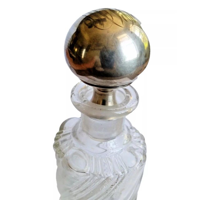 Discover this exquisite vintage perfume bottle featuring a clear glass body with a sterling silver stopper. The stopper is...