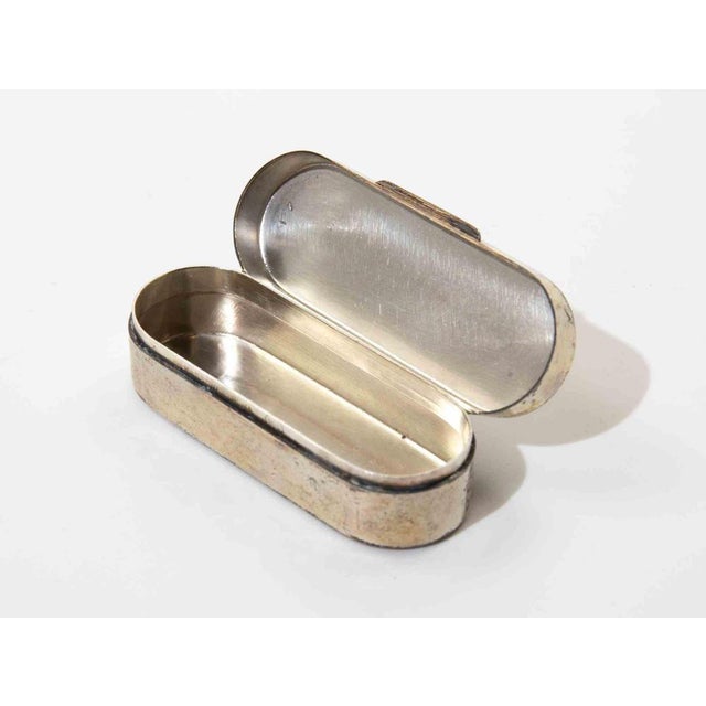 A refined sterling silver hinged box of elongated oval form, featuring softly rounded ends and a clean minimalist...