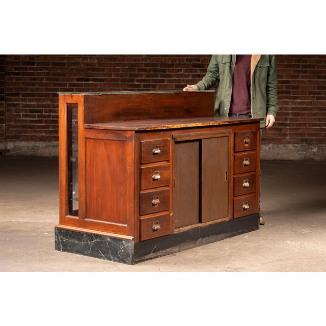 Substantial oak display counter featuring a glass-front upper showcase set atop a marble base, with a working counter-...
