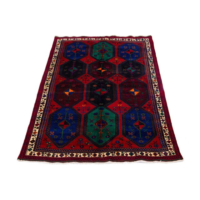 A vintage hand-knotted Bidjar wool rug with a red field and multicolor accents allover the tribal pattern. This rug...