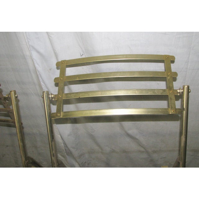 Mid Century Modern folding chairs in gold toned metal with dark wood slats seats. They fold flat for easy storage and...
