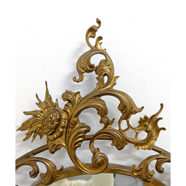 MADE IN ITALY, ca. 1940s/1950s Oval wall mirror with brass frame decorated with floral motifs and a cornice, mirrored...