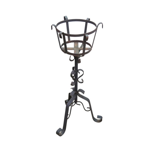 This vintage wrought iron plant stand showcases a classic, hand-forged gothic or brutalist design characterized by a...