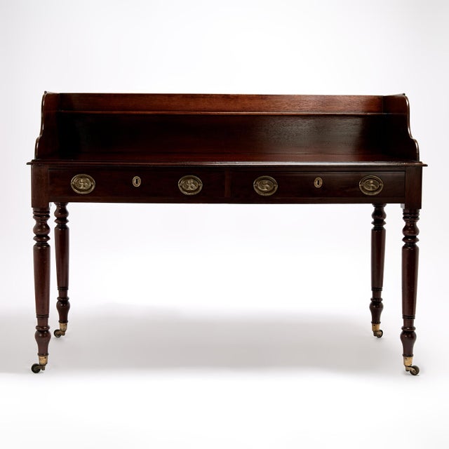 Handsome 19th Century British Colonial server handcrafted in mahogany featuring a dramatic gallery with shelf on a case...