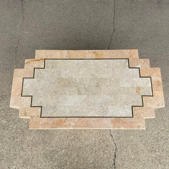 This is a Maitland-Smith tessellated pink and cream stone geometric pedestal with inlaid brass accents.