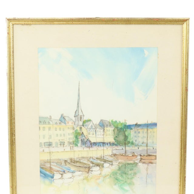 A charming vintage watercolor painting of a small french harbor town, set in a sleek gold frame with an acrylic front;...