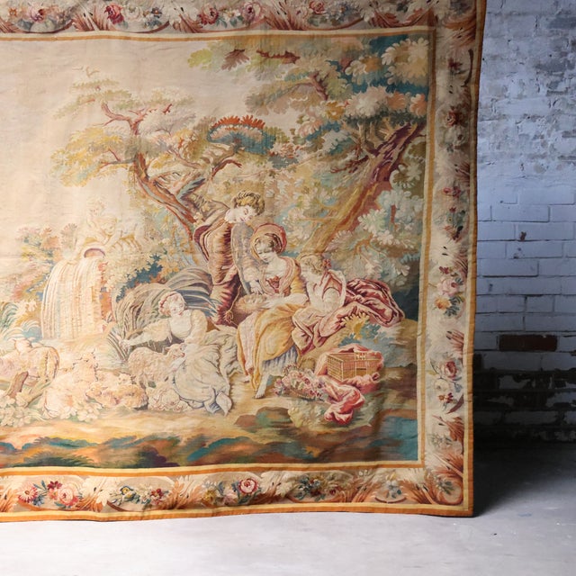 19th-century French Aubusson tapestry woven in wool, depicting a serene picnic scene with a flock of sheep gathered by a...