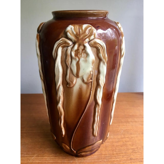 This caramel colored ceramic vase features an ornately crafted floral motif in relief on four sides. With its understated...