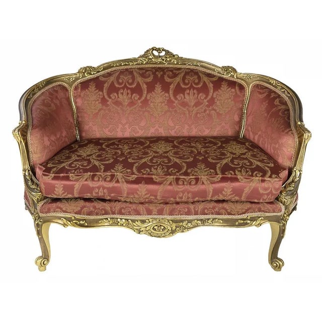 French handcrafted and gilded wood loveseat sofa circa 1950s. The sofa is upholstered with red and gold colour damask...