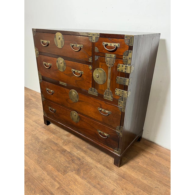A Taisho period Japanese tansu in elmwood mounted with unusual brass hardware rather than the more typical forged iron.