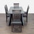 This dining set features a sturdy rectangular table with a modern angled leg design and six comfortable chairs. The dark...