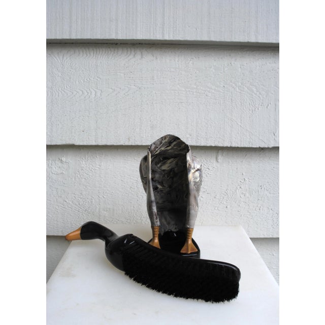 Duck shaped clothes brush. The head is the brush handle, the body is the storarge stand. The duck is marbled gray with a...