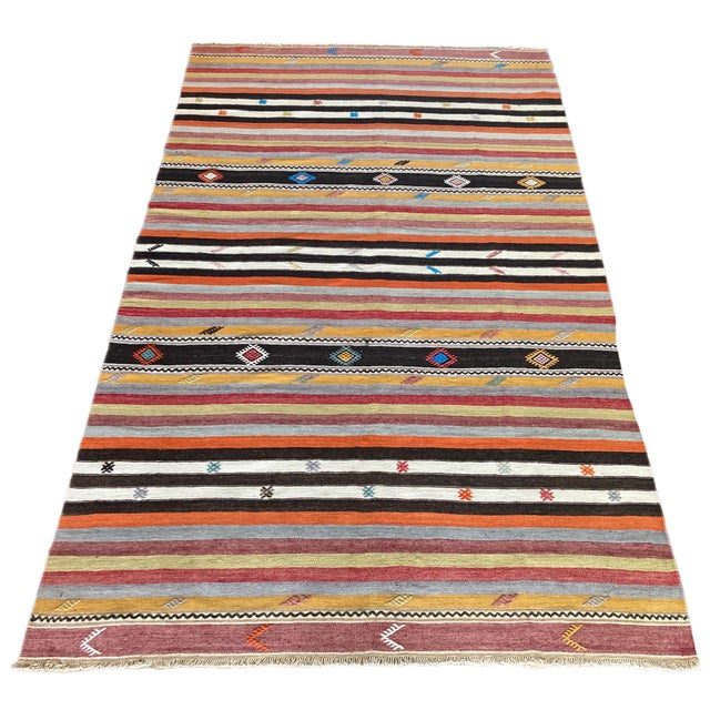 A beautiful vintage kilim, handwoven in central Turkey circa 1960 featuring a traditional, multicoloured banded design in...