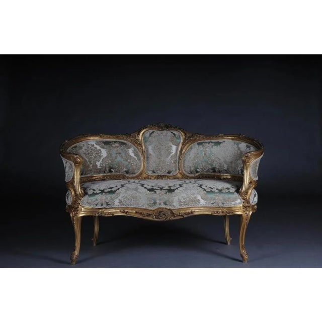 Solid beech wood, carved and gilded. Rising backrest framing with openwork rocaille crowning. Appropriately curved frame...