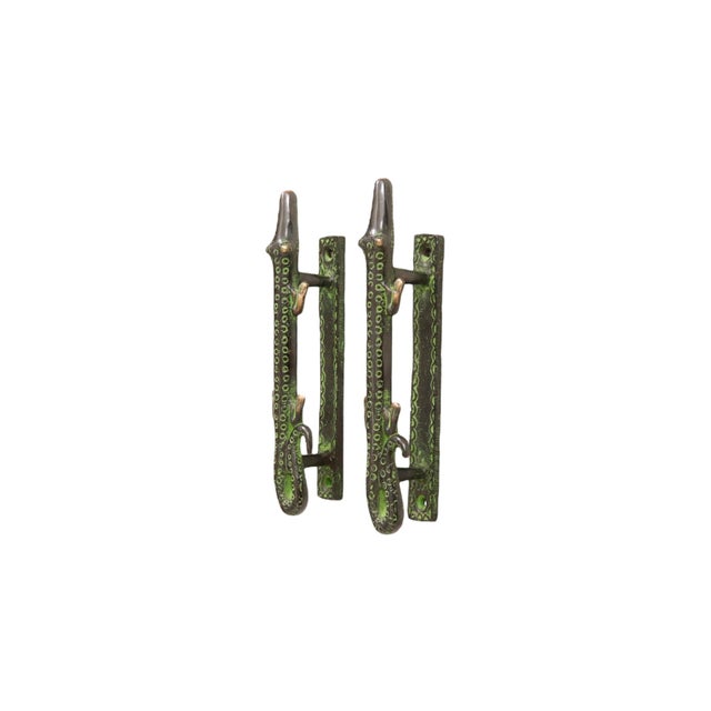 A pair of green brass alligator door handles or cabinet pulls. Pressed with simple details to convey skin, eyes and toes....