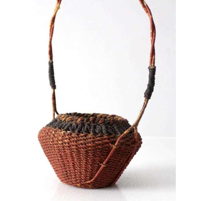 Early 20th century Southeast Asian basket with tightly coiled handwoven fibers in rust and black tones and a sculptural...