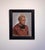 The artwork features a contemplative figure with a striking short hairstyle, dressed in a casual hoodie, creating an...