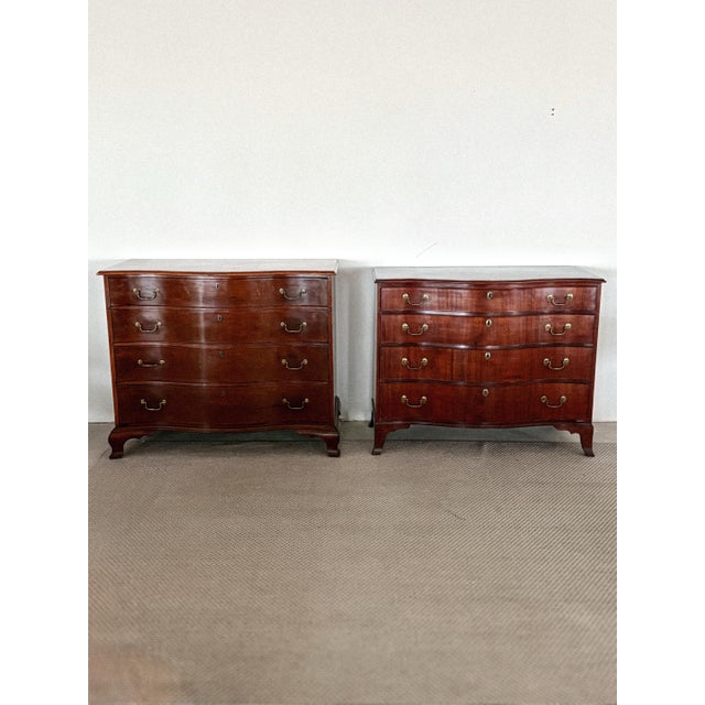 A beautifully assembled matched pair of Georgian mahogany serpentine-front chests of drawers, dating to the late 18th....
