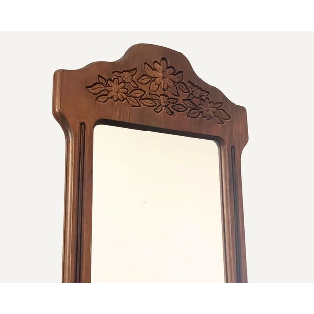 Vintage wall mirror with a carved wood frame featuring floral and leaf motifs at top and bottom. Scalloped silhouette with...